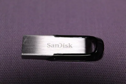 Boîtier argenté et noir d’une clé USB SanDisk Ultra Flair, photographié de face sur un tissu sombre