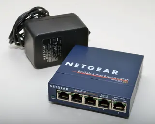 Switch NETGEAR GS105 bleu avec son adaptateur secteur noir sur fond blanc