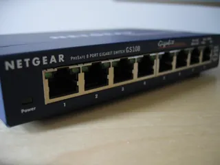 Façade bleue du switch NETGEAR GS108 et ses prises RJ45 sur un support en bois