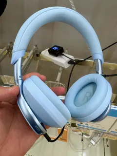 Casque soundcore Space One bleu ciel tenu dans une main, coussinets et intérieur de l’arceau visibles dans un magasin