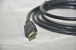 Photo illustrative d’un câble HDMI noir enroulé avec un connecteur visible ; visuel de connectique, pas la photo exacte du modèle UGREEN 40178
