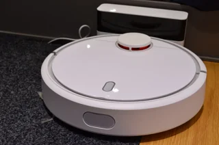 Ancien robot aspirateur Xiaomi blanc près de sa base ; photo illustrative, pas la photo exacte de Ecovacs DEEBOT T90 MAX OMNI ni preuve des accessoires fournis