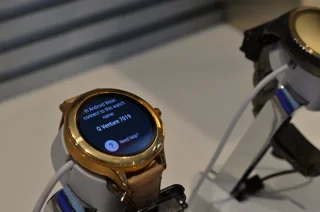 Ancienne montre Android Wear ronde dorée sur un présentoir ; photo illustrative, pas la photo exacte de Samsung Galaxy Watch9 40 mm Bluetooth graphite ni preuve du contenu du coffret