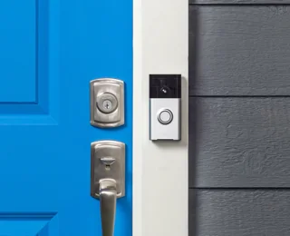 Ancienne sonnette vidéo Ring montée près d’une porte bleue ; photo illustrative, pas le modèle exact EZVIZ EP4 argent, judas avec écran ni le contenu de son coffret